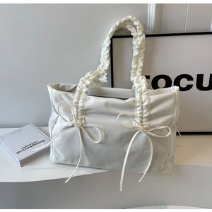 Detail van witte geplooide shopper met trekkoordbandjes en strikversieringen
