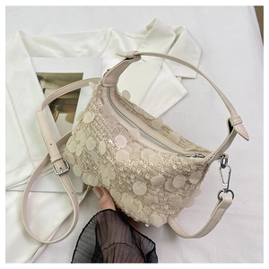 Close-up of off-white sequined handbag showing rich texture on a white shirt background