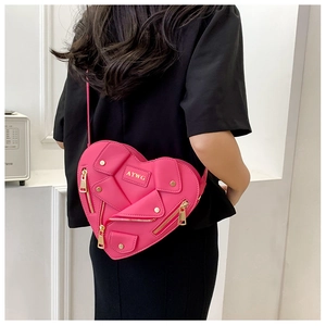 Detail of hot pink heart-shaped crossbody bag with gold zippers and biker jacket design