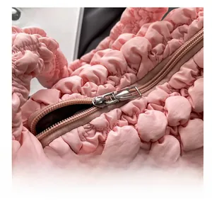 Detailed close-up of smooth silver metal zipper on pink bubble textured handbag