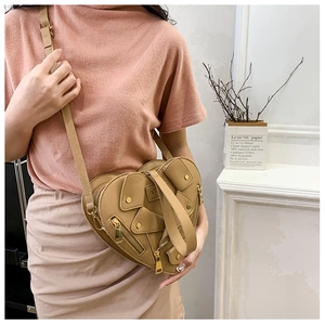 Detail of khaki heart-shaped biker style crossbody bag with metal zippers and studs