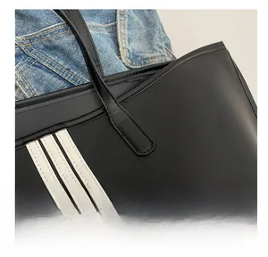 Close-up of precise stitching and three white stripes on a black nylon tote bag