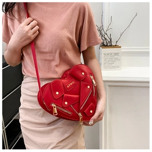 Detail of red heart-shaped biker bag with zipper elements and golden metal studs