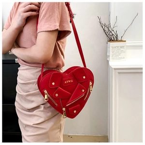 Detail of red heart-shaped crossbody bag featuring motorcycle jacket style and metallic studs