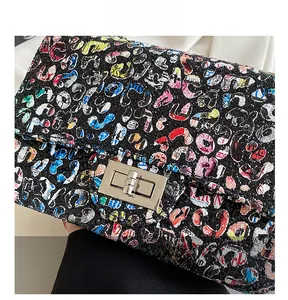 Close-up of graffiti print shoulder bag featuring a silver metal twist-lock buckle