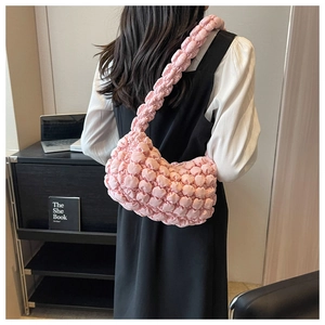 Detail view of pink bubble textured shoulder bag with pleated quilted design on a model
