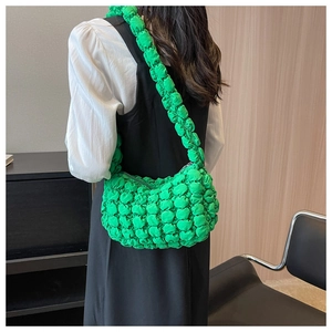 Detail of vibrant green popcorn bubble texture on a crescent shoulder bag worn by a model