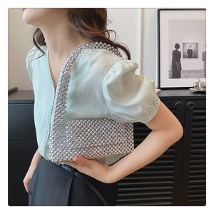 Close-up of silver beaded handbag with metallic studs and handcrafted woven texture