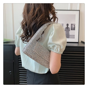 Detailed view of a silver beaded handmade handbag worn by a model in a trendy setting