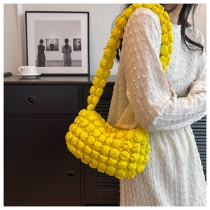 Detailed close-up of yellow bubble textured shoulder bag with pleated elastic fabric