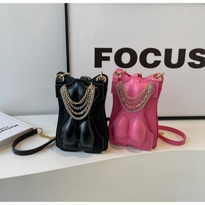 Detail of trendy female torso-shaped crossbody bags in black and pink with metal chains