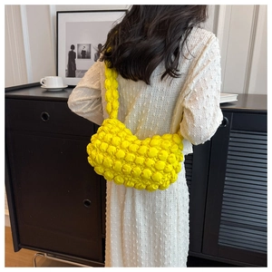 Detail of bright yellow bubble texture shoulder bag styled with a white summer dress