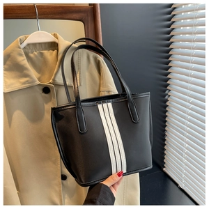 Detail of black nylon tote bag featuring three vertical white stripes and dual handles
