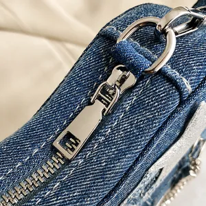 Macro shot of smooth silver metal zipper and D-ring on blue denim guitar bag texture
