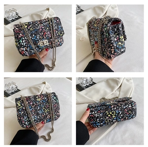 Detail view of colorful graffiti chain bag with gold metal clasp and textured finish
