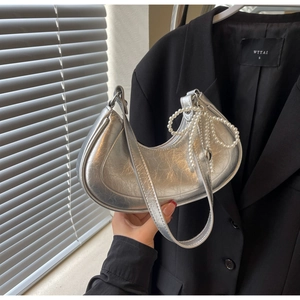 Detail of silver metallic crescent bag with a large pearl bow charm and cracked texture