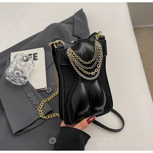 Detail of artistic body torso relief on black leather crossbody bag with layered metal chains