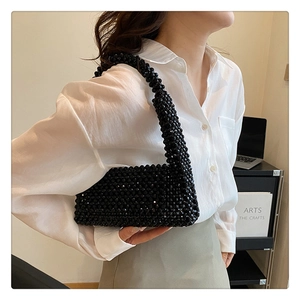 Detail of hand-woven black beaded shoulder bag with glossy finish and compact texture
