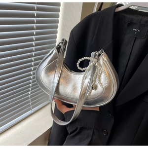 Macro detail of silver pleated crescent bag with pearl chain and metallic leather texture