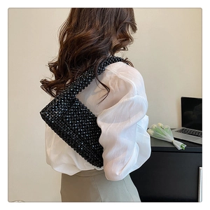 Fashionable black beaded shoulder bag shown on a model in a minimalist office setting