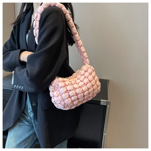 Detail of pink bubble texture shoulder bag showing pleated fabric and puffy strap on a model