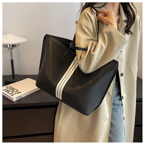 Macro detail of large black tote bag with three white stripes and polished leather finish