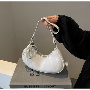 Close-up of white crescent crossbody bag featuring leather texture and beaded zipper detail