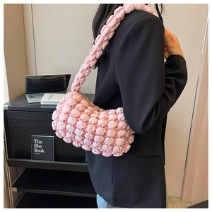 Detail of pink bubble texture shoulder bag with wide strap on a female model