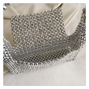 Close-up of handmade silver beaded shoulder bag with metallic punk rivet mesh texture
