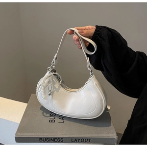 Detailed view of white crescent bag with pearl charm and adjustable shoulder strap