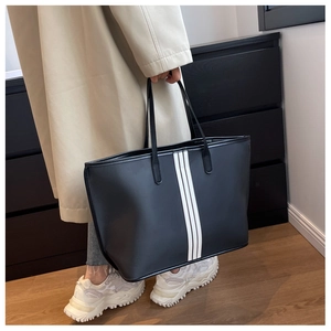 Detail of black nylon tote bag with white vertical stripes and long handles for shoulder wear