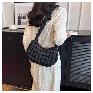 Detail of black pleated bubble bag showing 3D textured fabric and wide shoulder strap