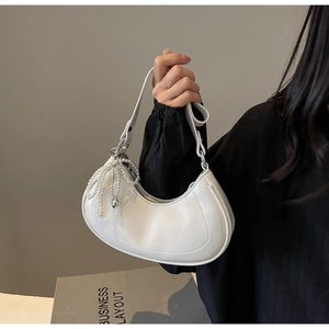 Detailed view of white croissant bag with elegant pearl chain and heart pendant
