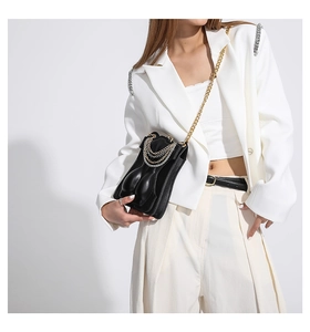 Detail view of a black crossbody bag featuring a unique 3D artistic female torso relief