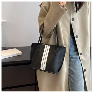 Detail of a black nylon tote bag with white vertical stripes and matte leather texture