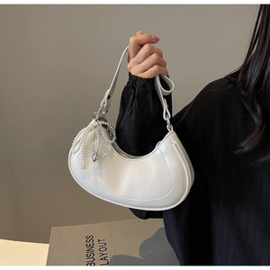 Detail of white crescent moon bag featuring a chic pearl tassel charm and leather texture