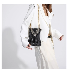 Detail of artistic female torso shaped crossbody bag with gold and silver layered chains