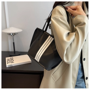 Close-up of minimalist black nylon tote bag with three white stripes and dual shoulder straps