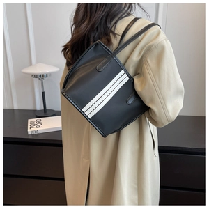 Detail view of black nylon tote bag with three white stripes worn by a model