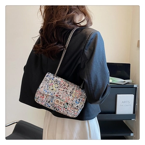 Detailed view of the colorful graffiti chain bag worn by a model in a leather jacket