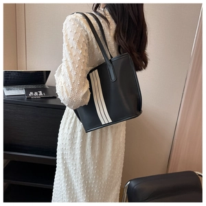 Detail of black nylon tote bag featuring three vertical stripes and spacious shoulder design
