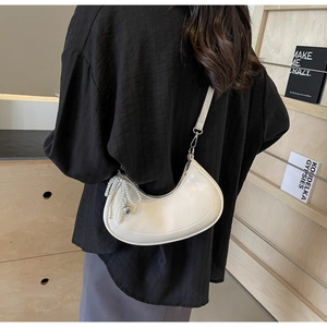 Detail of cream leather hobo bag with pearl heart pendant and minimalist shoulder strap