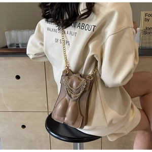 Detailed relief design of human torso on khaki crossbody bag with layered metal chains