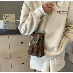 Detailed view of brown body-shaped crossbody bag with gold and silver chain accents