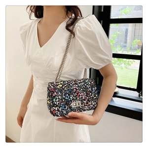 Close-up of colorful graffiti print crossbody bag with silver chain and metal twist lock