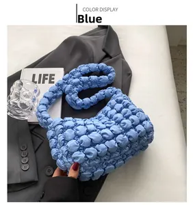 Detailed view of blue ruched bubble bag with quilted puff texture on grey fabric
