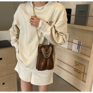 Detail of a brown 3D female torso sculpture crossbody bag with layered chain decor