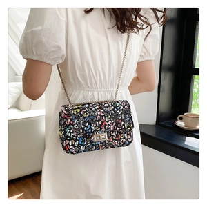 Detail showing colorful leopard print texture and silver twist lock on chain bag