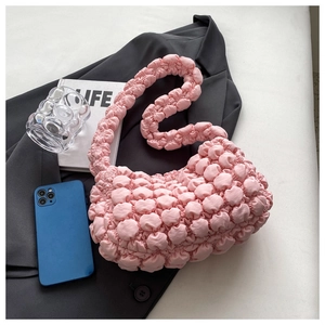 Detail of pink bubble texture shoulder bag placed on grey blazer for summer style