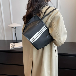 Minimalist black nylon tote bag with white stripes for women shown in a modern interior